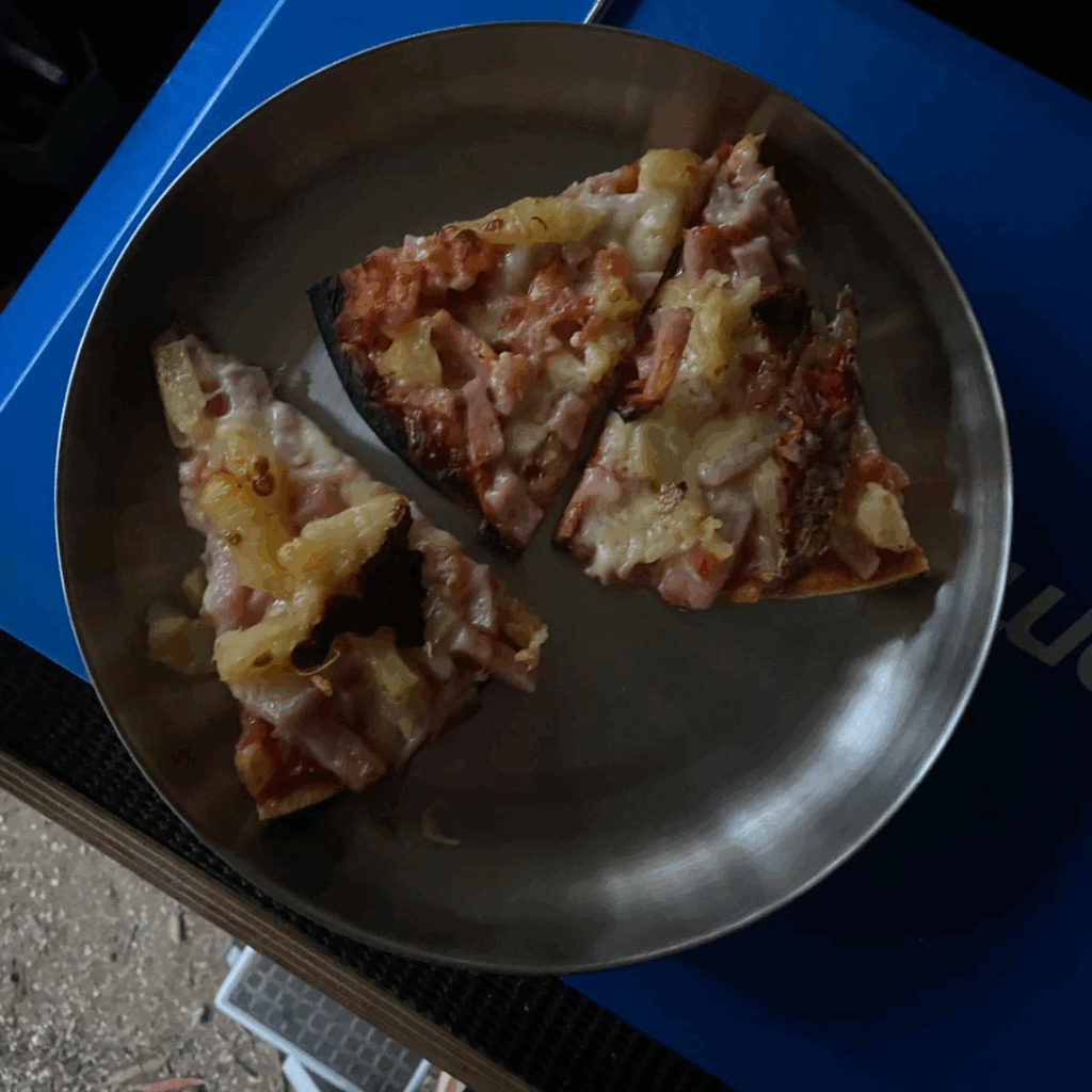 Pizza on metal plate cooked in camp oven while out tin the bush camping